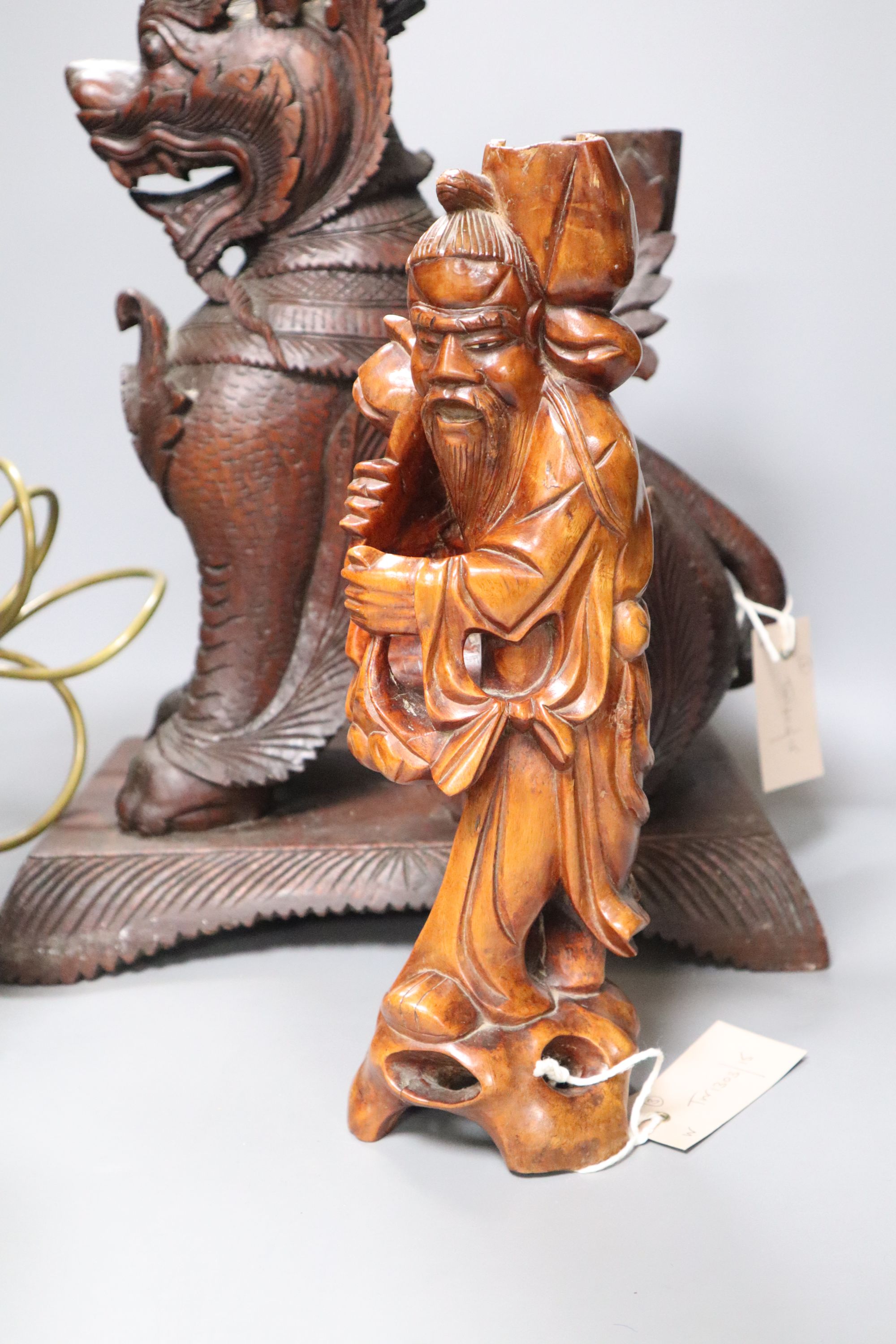 An Indonesian large carved wood model of a seated kylin, on plinth base and two Chinese rootwood carvings of elders, H approx 44cm (kyl
